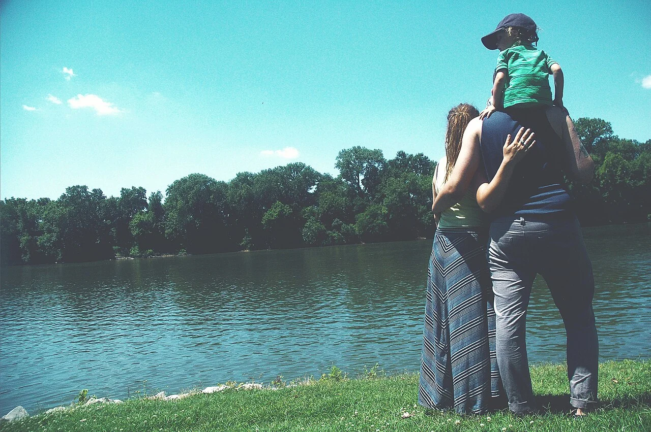 A family standing together beside a lake