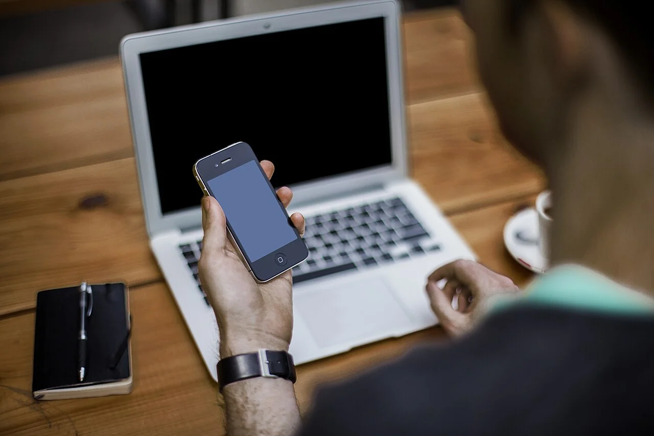 A person working with a smartphone and laptop